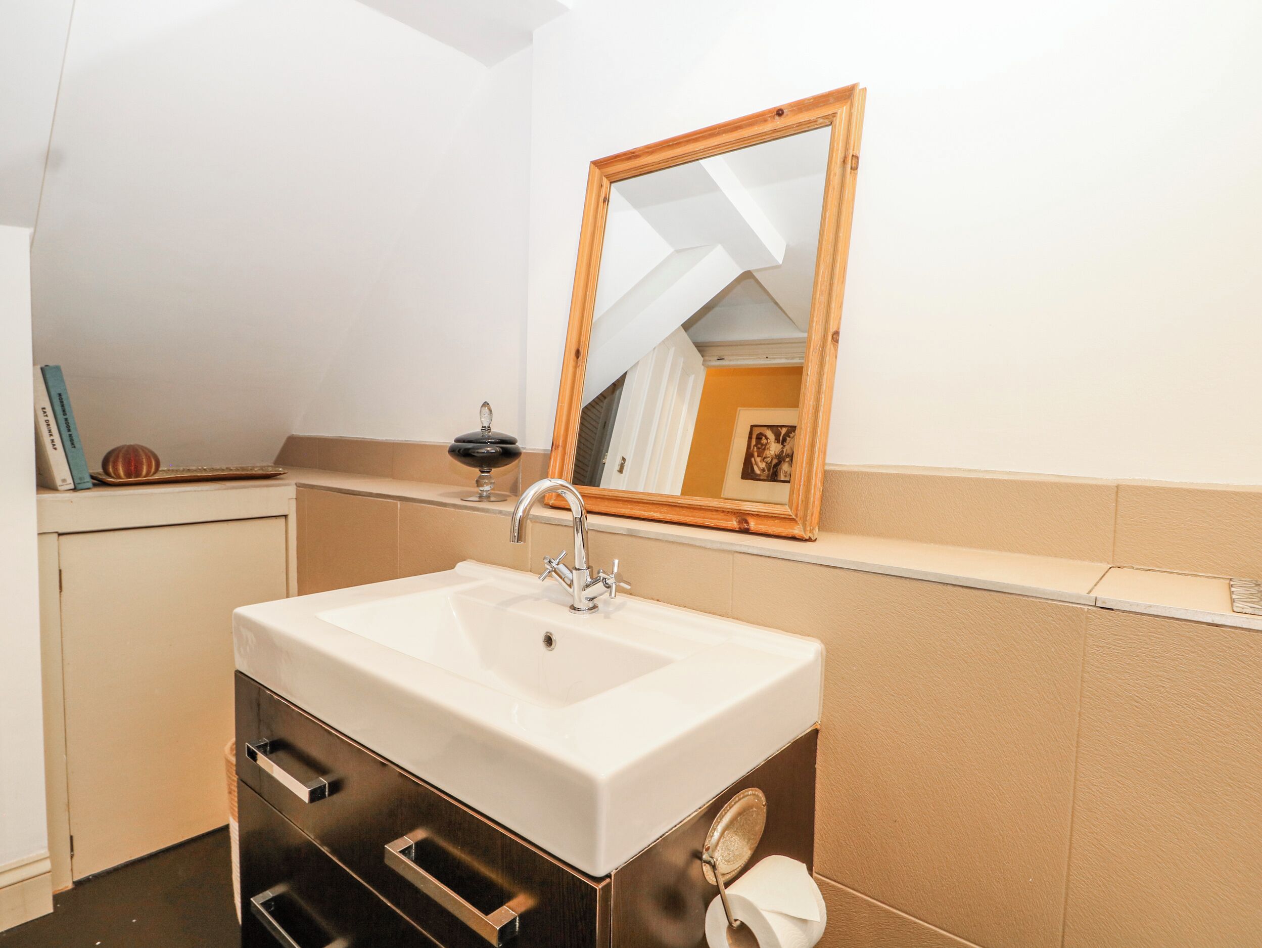 A bathroom with a sink, mirror, and towel dispenser.