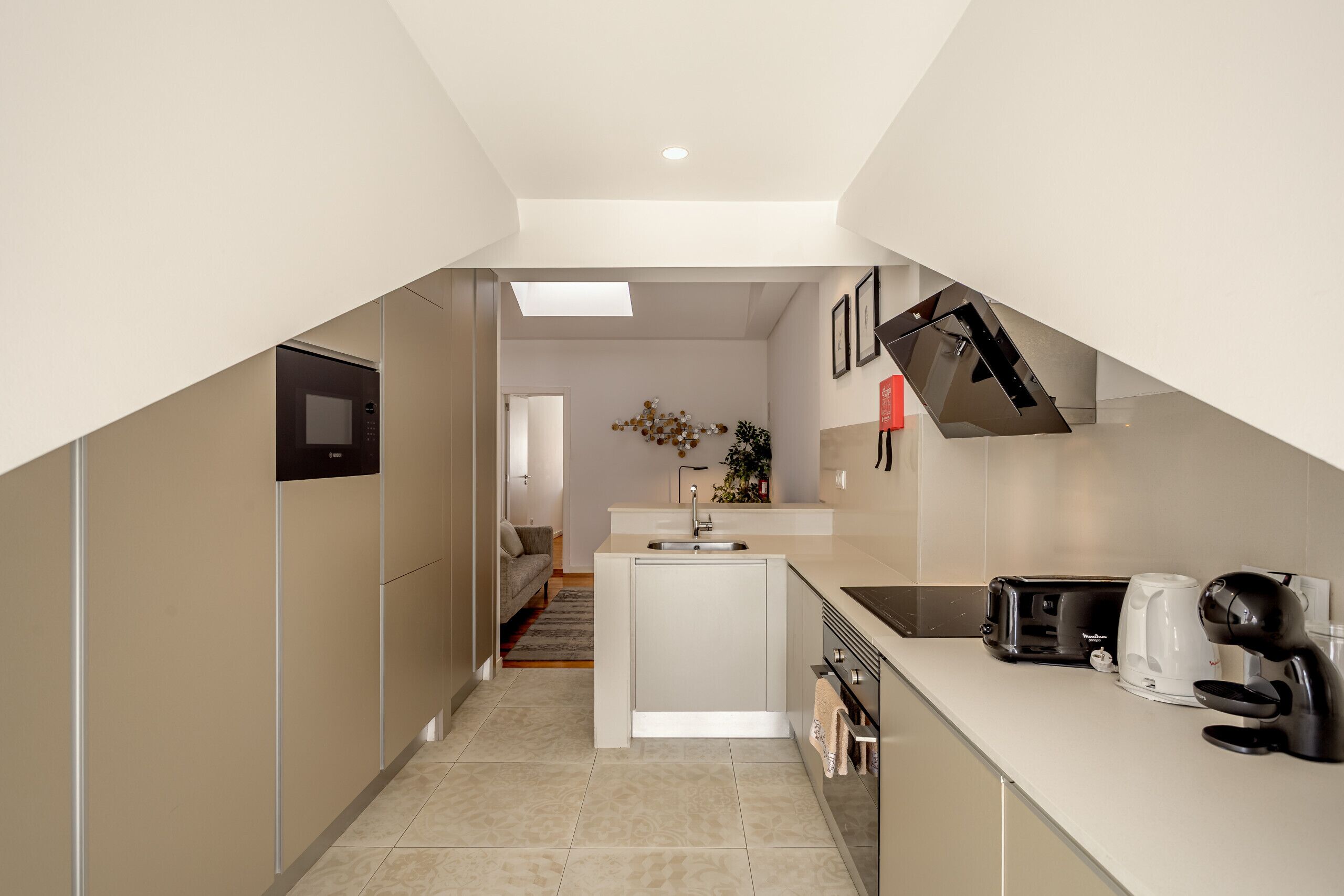 A modern kitchen with a built-in oven, a coffee maker, and a sink.