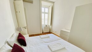 A bedroom with a bed, pillows, a nightstand, a dresser, and a window. - Downtown Riverside III by Homing (Lisbon)