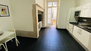 A kitchen with white cabinets, a black tiled floor, a dining table with a chair, and a framed picture on the wall. - Downtown Riverside III by Homing (Lisbon)