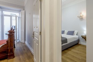 A bedroom with a bed, a wooden wardrobe, and a door leading to another room. - Marques DE Pombal Vintage by Homing (Lisbon)