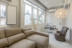 Ein modernes Wohnzimmer mit einem beigen Sofa, einem Esstisch mit Stühlen und einer dekorativen Stehlampe.