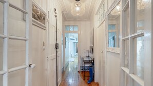 Un pasillo con puertas blancas, suelo de madera y un candelabro.
