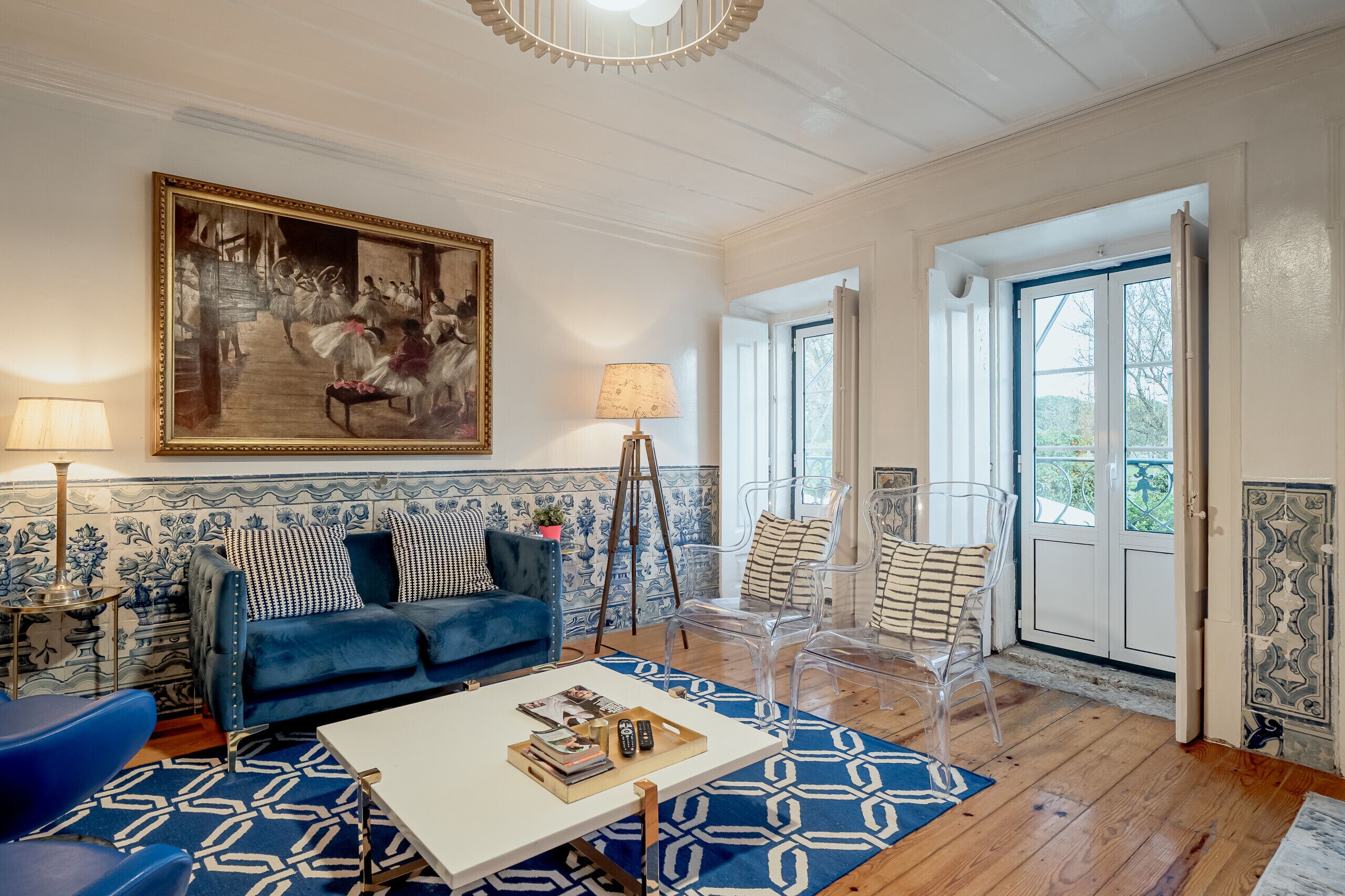 A living room with a blue sofa, a white coffee table, and a large painting on the wall.