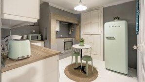 Una cocina compacta con microondas, tostadora y un refrigerador verde claro.