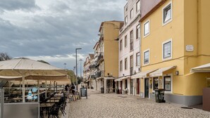 Una calle adoquinada con mesas al aire libre y edificios amarillos.