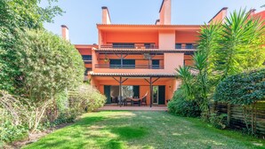 Un edificio su due piani con un portico coperto, immerso nel verde.