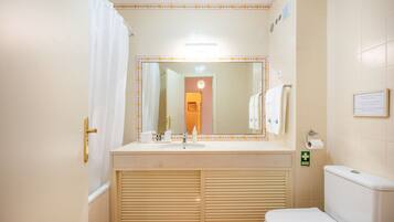 A bathroom with a sink, toilet, and mirror.