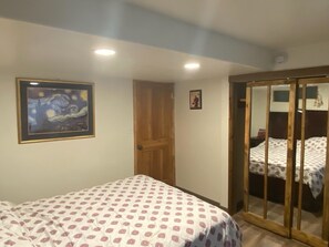 Een slaapkamer met een bed, een deur en een schilderij aan de muur.