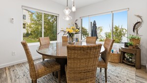 Un coin repas avec une table ronde, des chaises en osier et un vase rempli de fleurs.