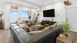 Un salon moderne avec un canapé en cuir, un téléviseur à écran plat et une cheminée.