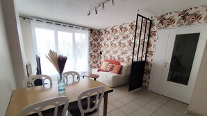 Een eetgedeelte met een tafel, stoelen, een bank, een decoratieve vaas en een schuifdeur.