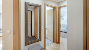 Un pasillo con puertas de madera, un banco y un espejo.