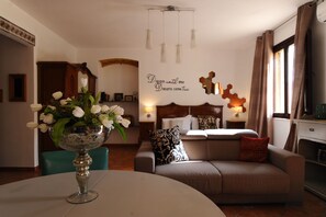 Un salon moderne avec un canapé, une table basse ornée d’un vase de fleurs, un lit avec une tête de lit et un mur sur lequel est inscrite une citation inspirante.