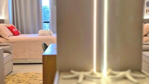 Een moderne hotelkamer met een bed, een bank, een bijzettafeltje en uitzicht op de omgeving.