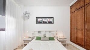 A bedroom with a bed, nightstands, a fan, a large wooden wardrobe, and a framed picture on the wall. - Vacation Apartment 'Almar We Go, Apartmento Entero' with Shared Terrace and Wi-Fi (Alcalá)