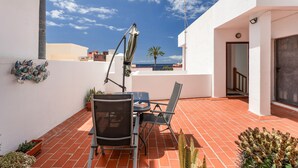 An outdoor patio with a table and chairs, a metal umbrella, and potted plants. - Vacation Apartment 'Almar We Go, Apartmento Entero' with Shared Terrace and Wi-Fi (Alcalá)