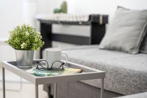 Une petite table sur laquelle se trouvent un pot de fleurs, une tasse et une paire de lunettes.