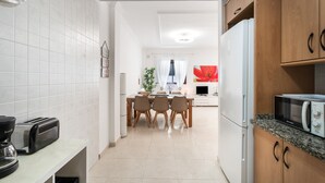 A modern kitchen with white tiles, a dining area with a table and chairs, and a microwave on the countertop. - Vacation Apartment 'Almar We Go, Apartmento Entero' with Shared Terrace and Wi-Fi (Alcalá)