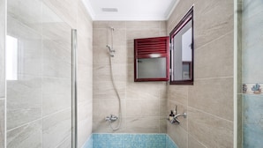 A bathroom with a glass shower enclosure, a tiled bathtub, and a mirror with a red frame. - Vacation Apartment 'Almar We Go, Apartmento Entero' with Shared Terrace and Wi-Fi (Alcalá)