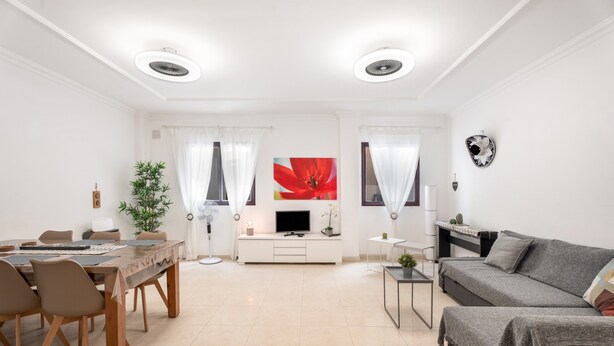 A modern living room with a dining area, a sofa, a TV, and a plant. - Vacation Apartment 'Almar We Go, Apartmento Entero' with Shared Terrace and Wi-Fi (Alcalá)