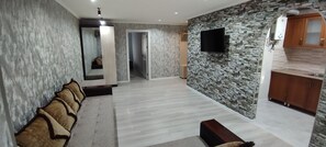 Un salon moderne avec un mur d’accent en pierre, un téléviseur à écran plat et un meuble en bois.