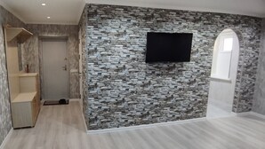 Ein Flur mit Steinwand, einem Wand-Fernseher und einem Holzschrank.