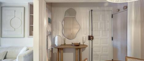 Un interno moderno con un tavolo da pranzo in legno, un divano bianco e uno specchio decorativo.