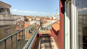 A balcony with a table and chairs, overlooking a cityscape with red-roofed buildings. - Downtown Modern Apartments by Homing (Lisbon)