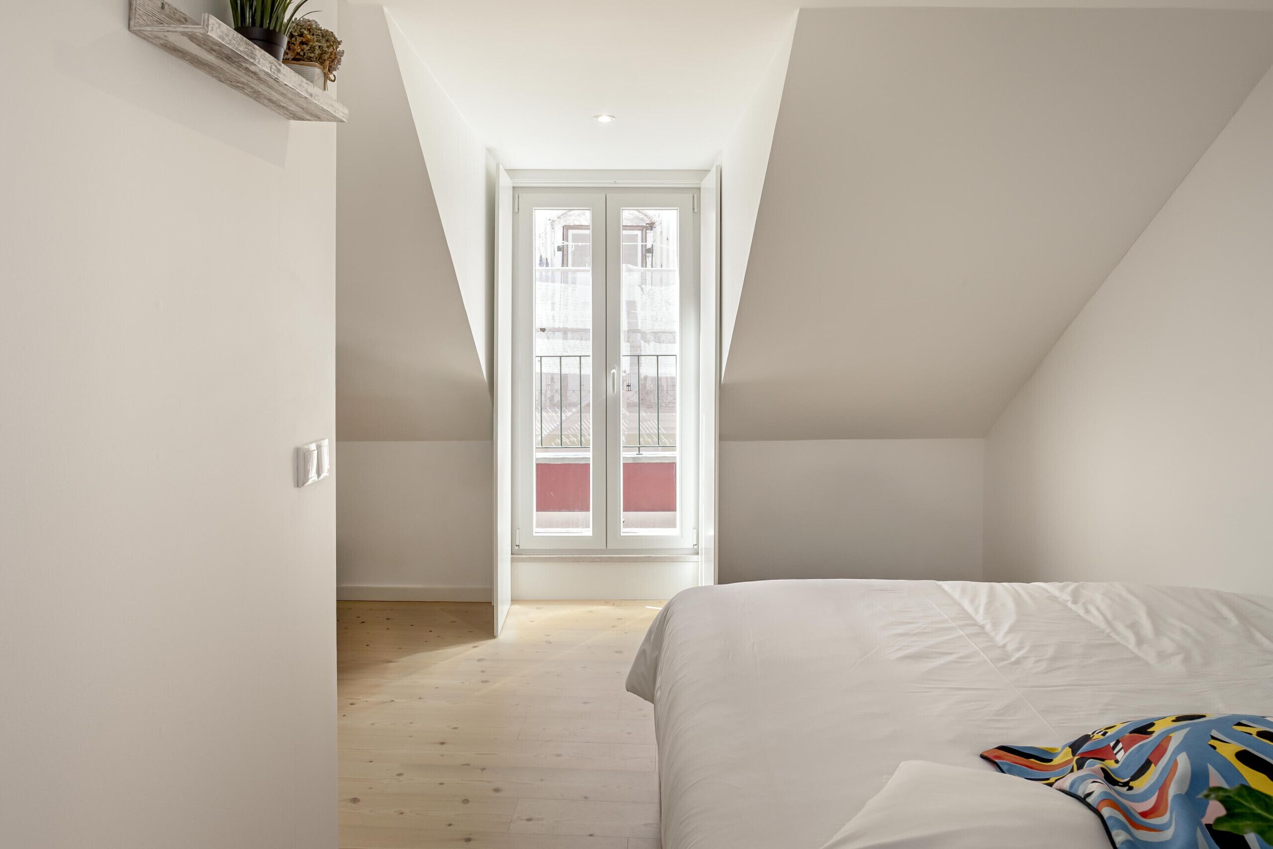 Una camera da letto con travi a vista, un letto, una finestra e pavimento in legno.