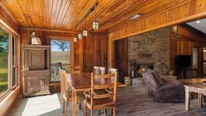 Un interior de madera con una mesa de comedor, sillas, chimenea y televisor.