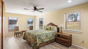 Un dormitorio con cama, una silla, una mesita de noche, una lámpara y un ventilador de techo.