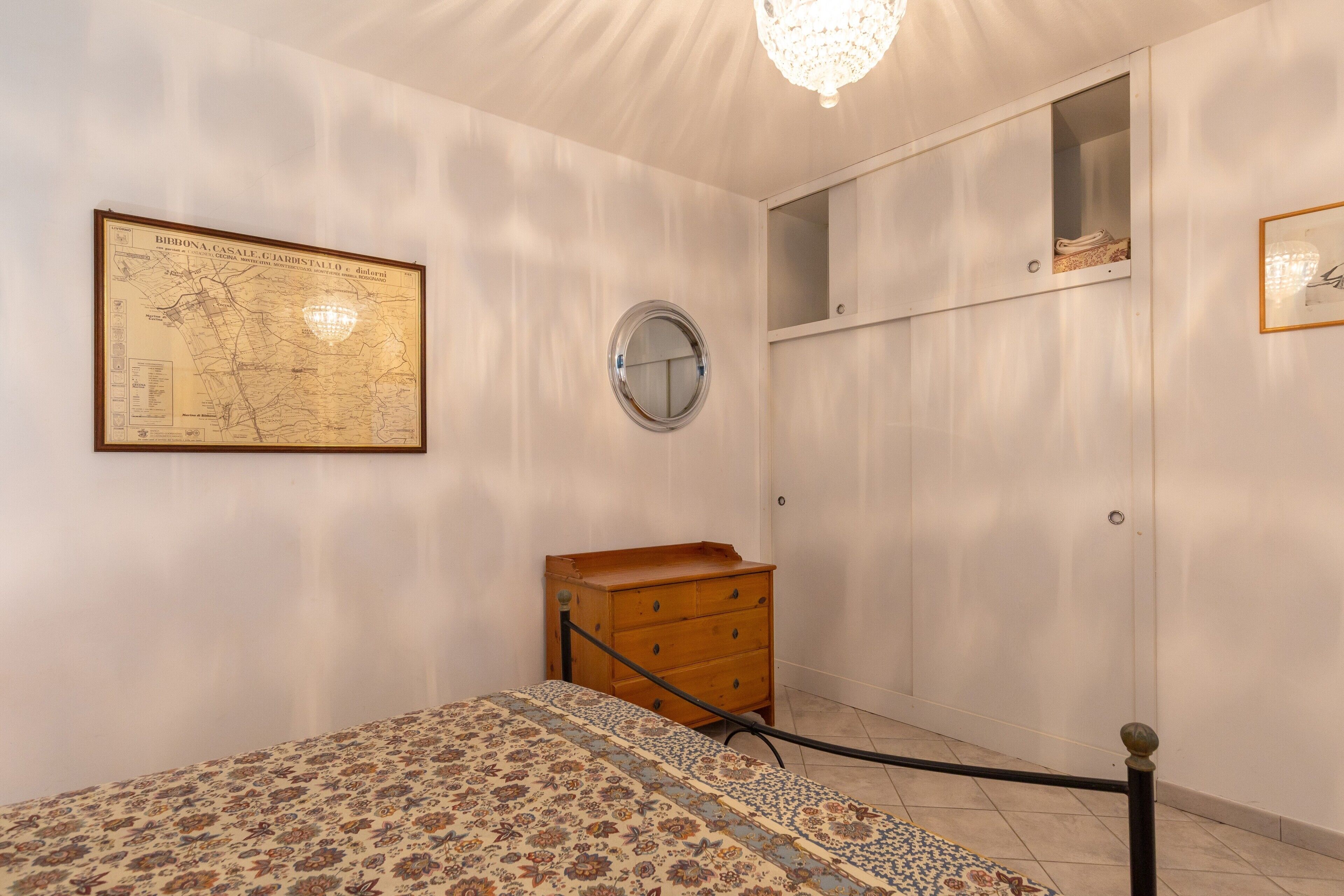 A bedroom with a bed, a dresser, a map on the wall, and a wardrobe.