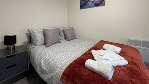 A bedroom with a bed, pillows, a blanket, a nightstand, a lamp, and a painting on the wall. - Downtown Sheffield Retreat (Sheffield)