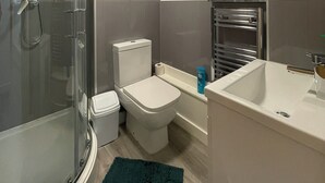 A bathroom with a glass-enclosed shower, a toilet, a sink, and a towel rack. - Downtown Sheffield Retreat (Sheffield)