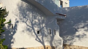 A white building with a curved facade, a small window, and the text 'EL REFUGIO' on the right side. - Minorcan house (S'Algar)
