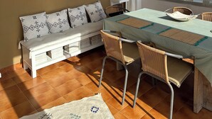 A dining area with a table, chairs, a bench, a bookshelf, and a large abstract painting. - Minorcan house (S'Algar)