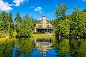 A house with a large balcony, surrounded by trees and a lake. - Spa & Private beach by the Lake | Repère du Cerf (Saint-Côme)