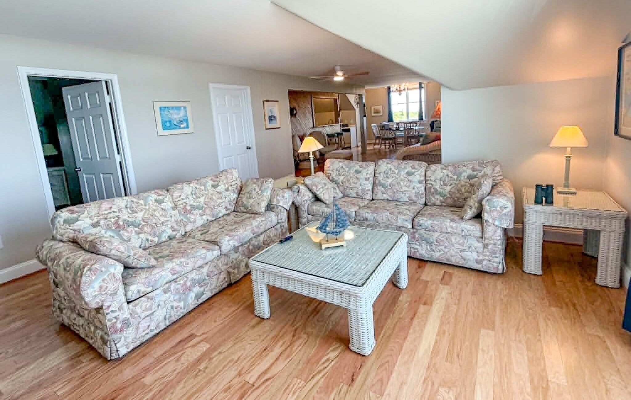 A living room with a sectional sofa, a wicker coffee table, and a lamp.