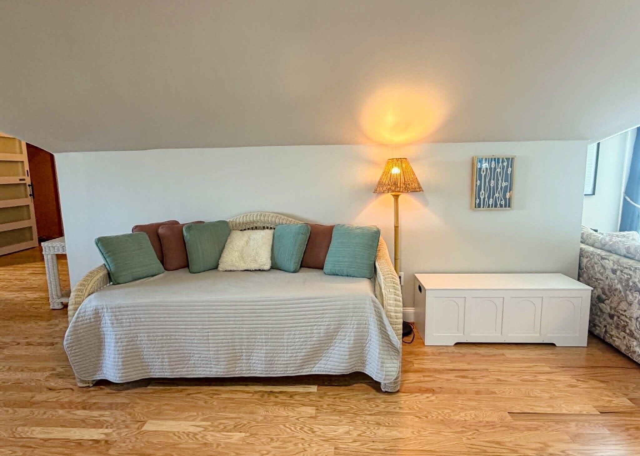 Une chambre à coucher comprenant un lit, des tables de chevet, une lampe, un canapé et une œuvre d’art murale.