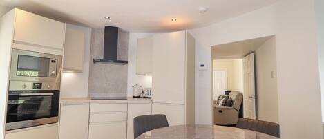 A modern kitchen with built-in appliances, a dining table, and chairs.