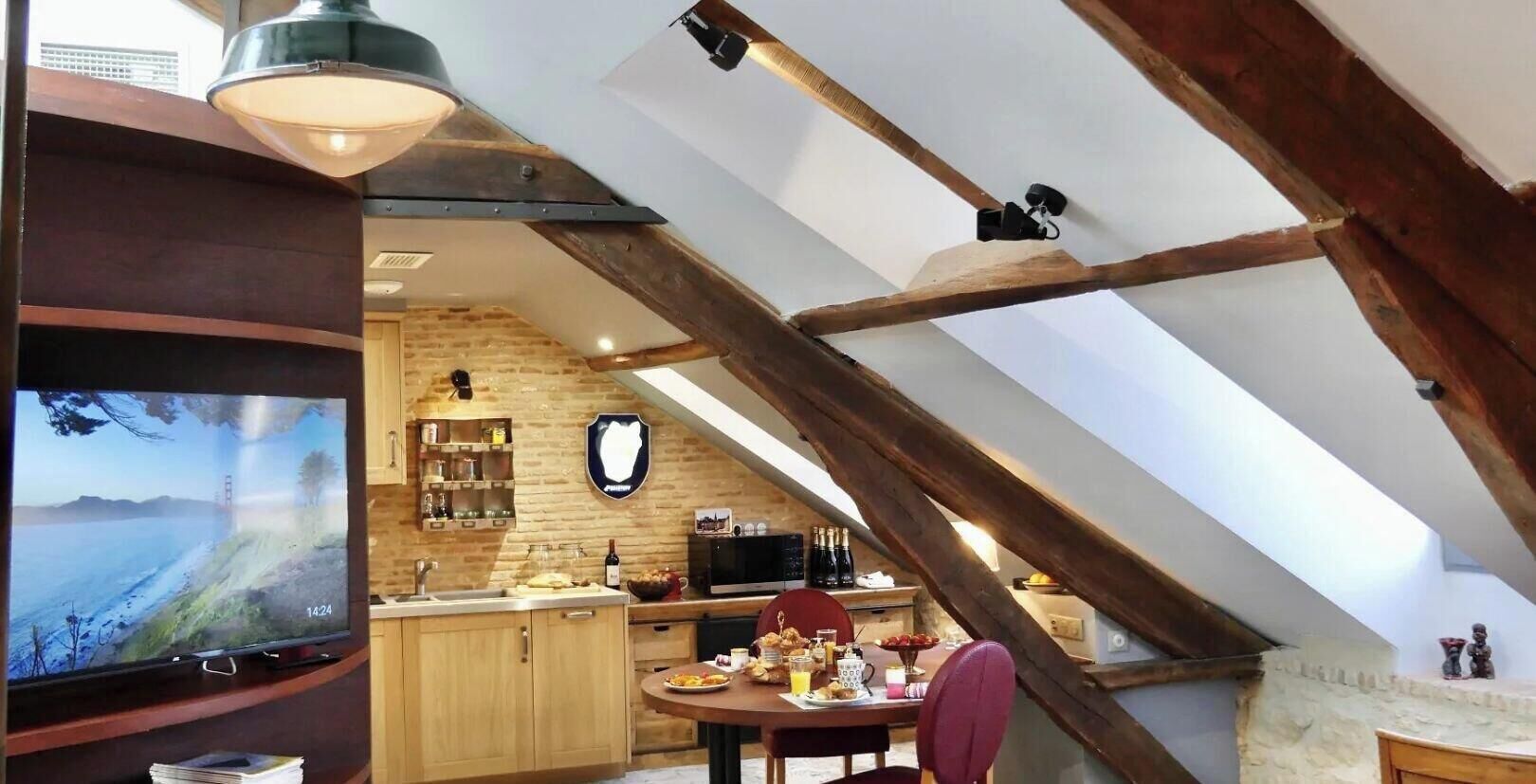 A cozy kitchen with a TV, wooden cabinets, and a dining area with a table and chairs.