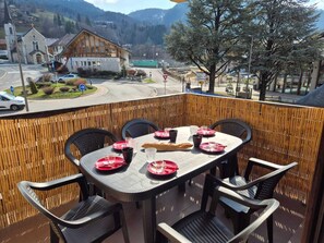 Una terraza con mesa lista para comer, con vistas a un pueblo y una montaña al fondo.