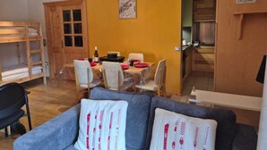 Un soggiorno accogliente con divano, tavolo da pranzo con sedie, una cuccetta e angolo cottura.