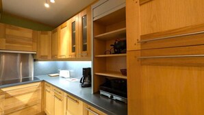 Cucina con mobili in legno, piano di lavoro in acciaio inossidabile e una macchina da caffè.