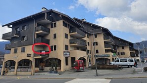 Un edificio a più piani con balconi, un ristorante chiamato 'Le Peille' e una farmacia.