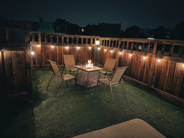 An outdoor patio with a fire pit, four chairs, and a wooden fence. - Riverwalk Path! Heart of South Main w/ Peak Views (Buena Vista)