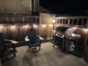 An outdoor patio with a grill, chairs, and a wooden fence. - Riverwalk Path! Heart of South Main w/ Peak Views (Buena Vista)