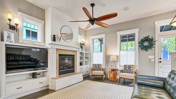 A living room with a fireplace, television, sofa, and ceiling fan. - Riverwalk Path! Heart of South Main w/ Peak Views (Buena Vista)