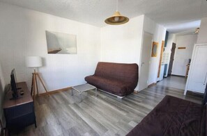 Ein Wohnzimmer mit braunem Sofa, einem kleinen Tisch, einer Lampe und einem Bild an der Wand.